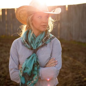 Blonde woman in cowgirl hat shows another angle of her Fringe Scarf, Kingman Turquoise.