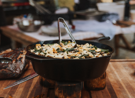 A cast-iron skillet full of pig roast sitting on a wooden table.