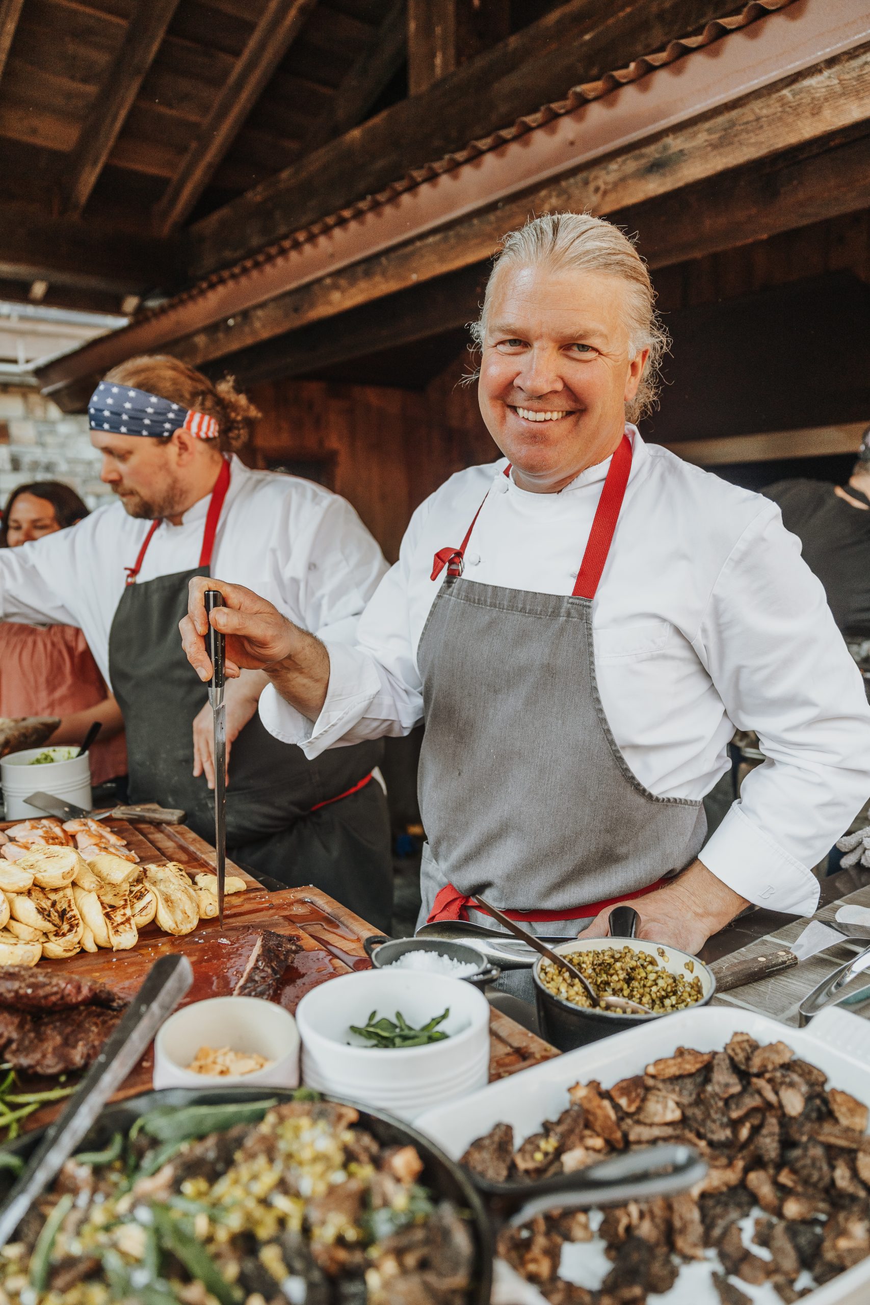 Chef Joshua Drage smiles at the camera while cooking with fellow chef's at The Ranch at Rock Creek's Ranch Carnival.
