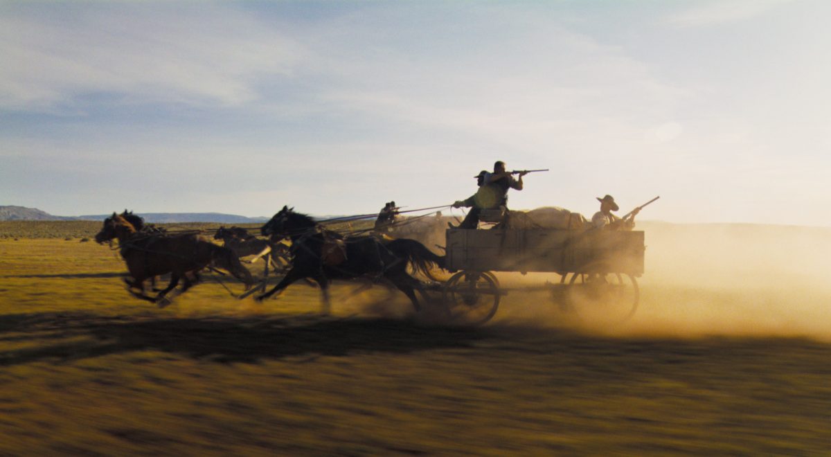 A horse carriage pulling gun-wielding men races across a plain in "Horizon: Part 1."